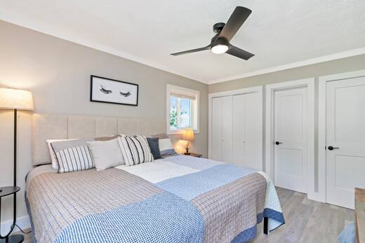 Primary bedroom with king bed, ceiling fan and upholstered headboard