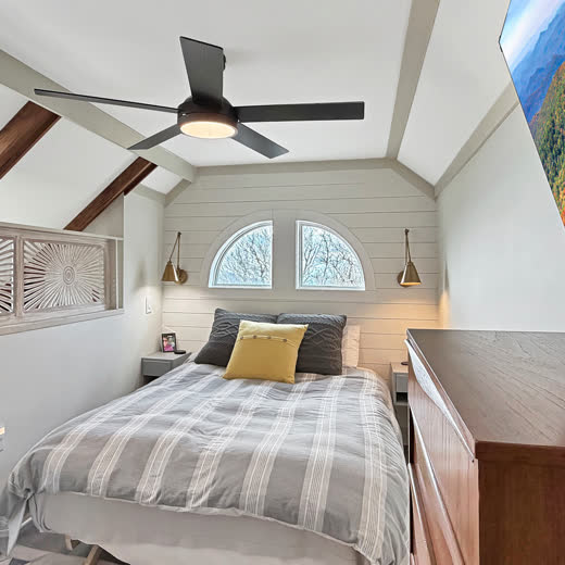 Bedroom with queen bed, vaulted ceiling and arched windows